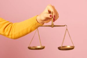 woman-hand-holding-a-balance-on-pink-background