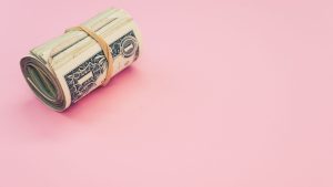 top-view-shot-of-a-bundle-of-rolled-up-american-banknotes-isolated-on-a-pink-background