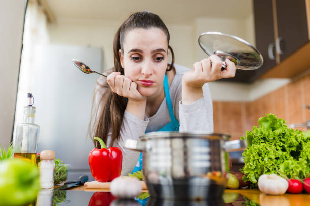 unhappy-woman-looking-at-pot-in-kitchen-food-preparing-failure-concept