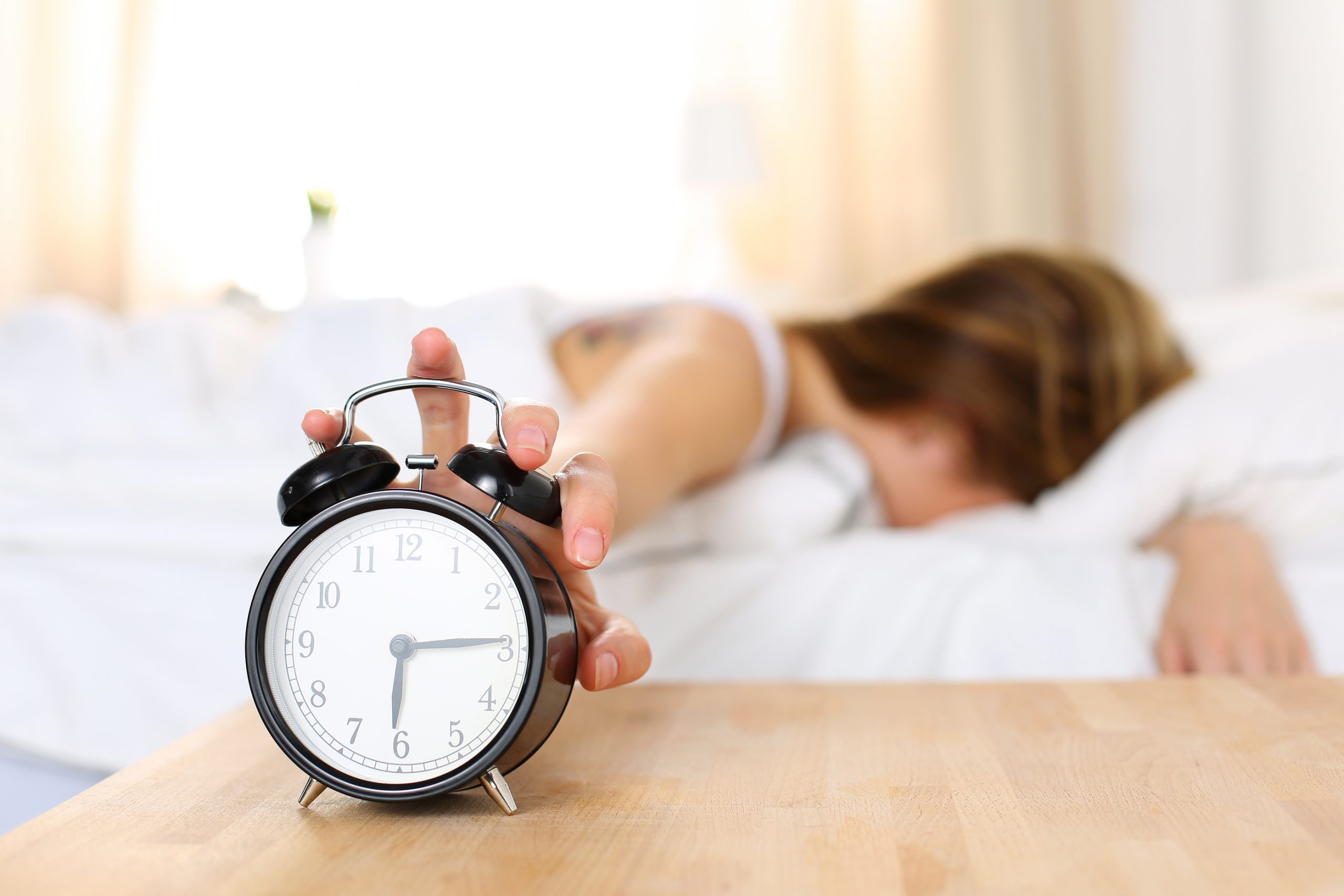 sleepy-young-woman-trying-kill-alarm-clock