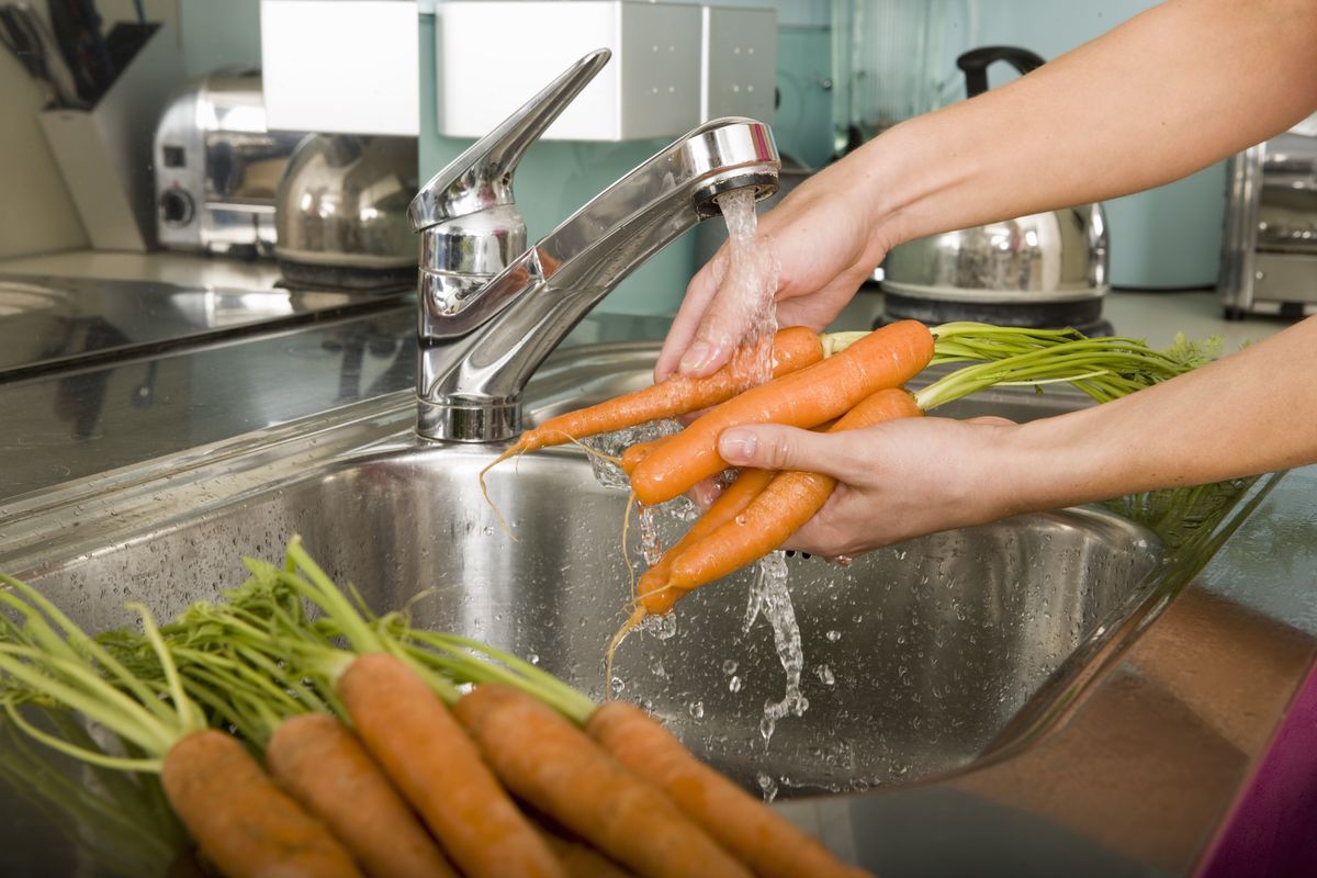 woman-washing-carrots-at-kitchen-sink-close-up-royalty-free-image-1586344130