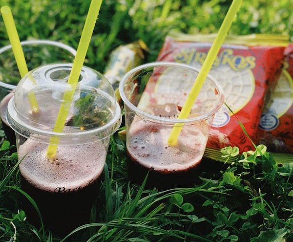free-photo-of-drinks-in-plastic-cups-with-straws-standing-on-the-grass