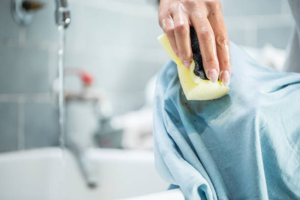 woman-cleaning-stained-clothing-with-cleaning-sponge