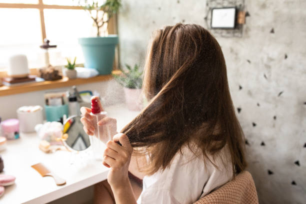 young-woman-using-hair-spray-in-bedroom-early-in-the-morning