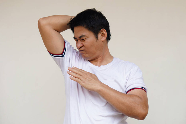 stock-photo-asian-man-checks-his-body-odor-feels-hot-raises-right