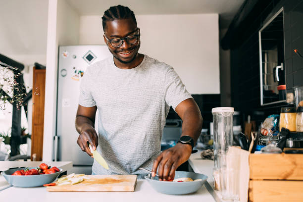 a-smiling-african-american-male-cutting-fruit-while-making-a-healthy-meal