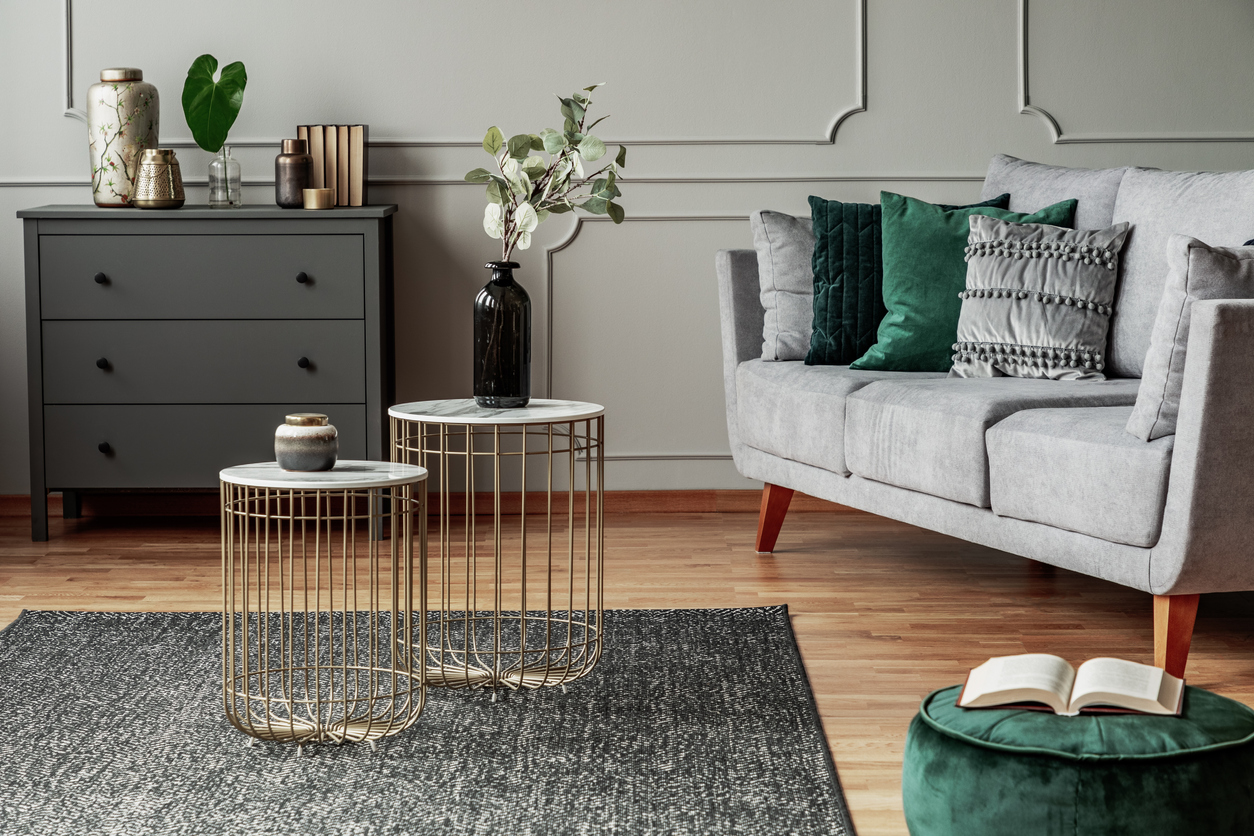 two-stylish-small-coffee-tables-with-marble-tops-in-front-of-elegant-grey-couch-with-emerald-pillows