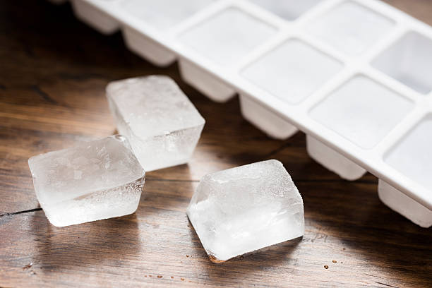 ice-cube-tray-filled-with-ice-cubes-and-three-lose-ice-cubes-against-dark-wood