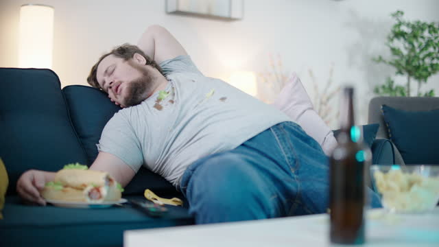 lazy-obese-bachelor-in-dirty-clothes-sleeping-on-sofa-at-home-among-hot-dogs